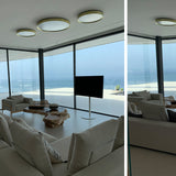 Lite Hole C 120 Aluminium LED ceiling lights in gold-trimmed white finish, mounted in a cluster of three above a bright living room with sofa, TV, and sea view.