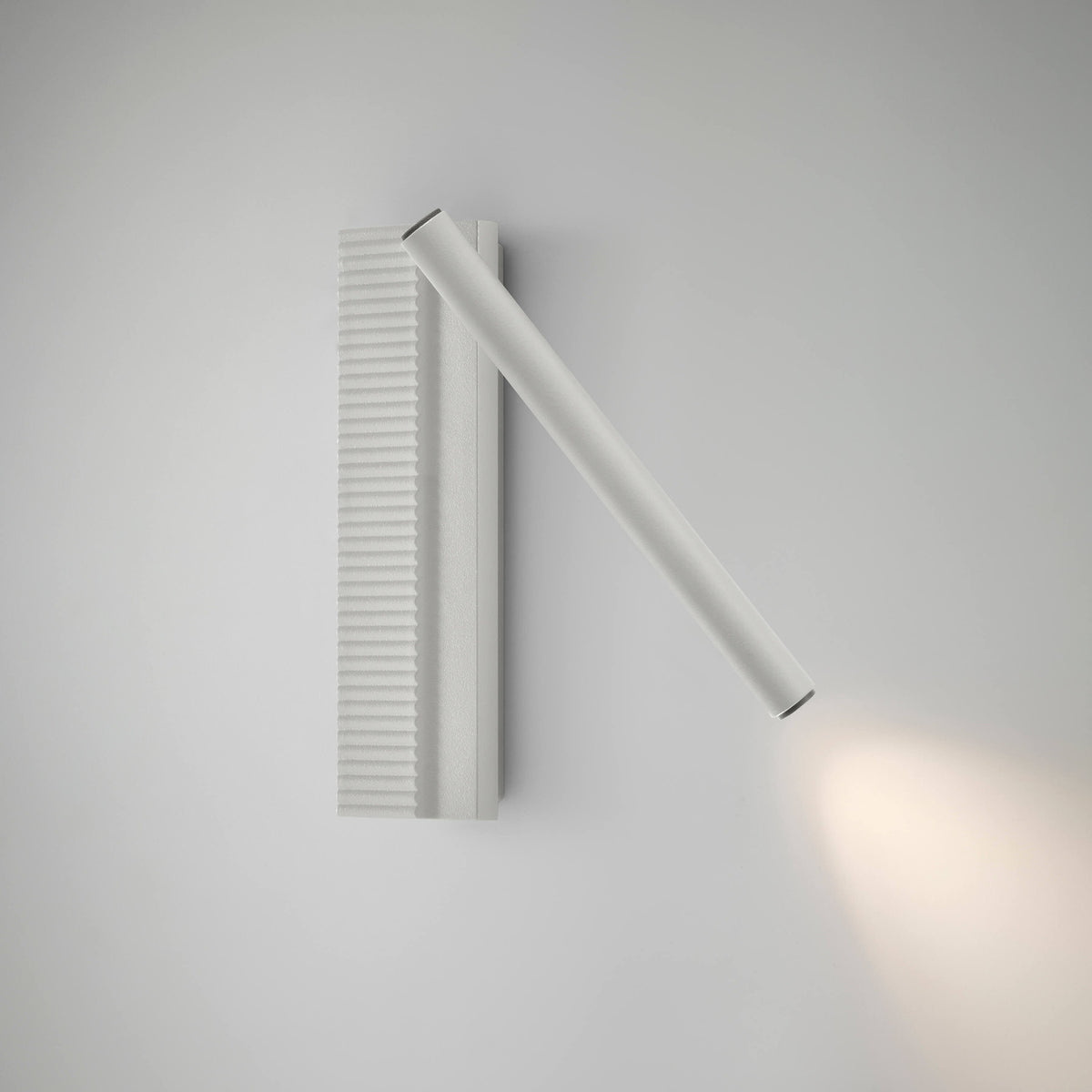Arid A/03 LED wall light in Textured White, with ribbed vertical aluminium back plate and an angled pivoting tube casting warm light, shown on a plain white background.