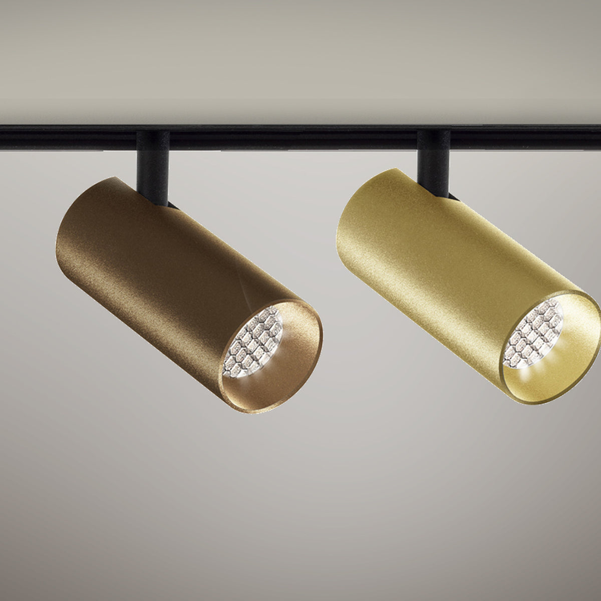 Street 5 Aluminium LED track spotlights in bronze and brushed brass finishes, cylindrical heads with honeycomb louvre lenses on a black track, shown against a plain background.