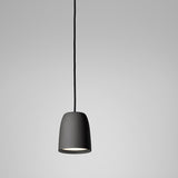 Nut S/10 pendant light with a small bell-shaped shade in textured black stainless steel, suspended on a black cord against a plain grey background.