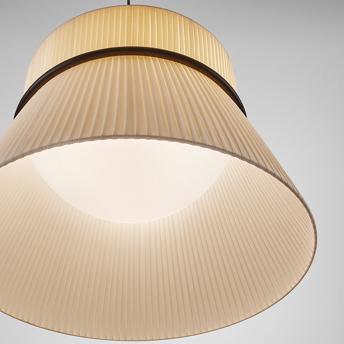 Close-up of the Folie S/60 pendant light in cream pleated ribbon fabric, showing the two-tier shade divided by a slim black ring, against a plain light background.