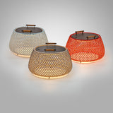Nans Bag/38/R rechargeable outdoor floor lamp, three low round woven baskets in beige, grey and red with dark lids and wooden carry handles, glowing warm light, on a plain grey background.