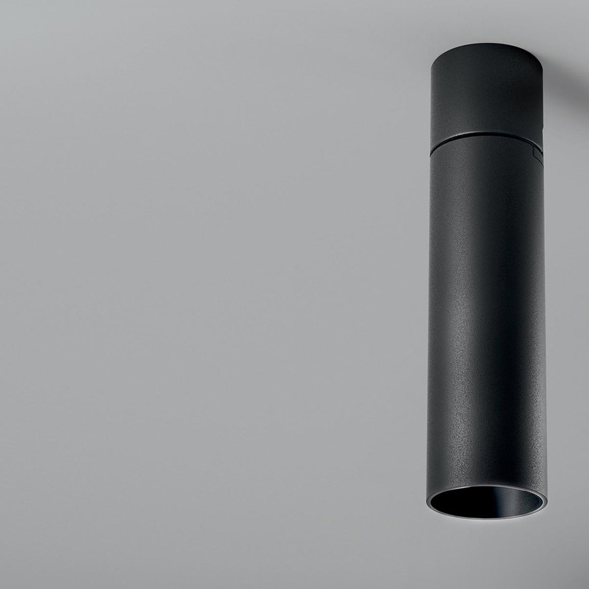 Lola Cylinder LED Ceiling Light in matte black, a slim single-tube downlight mounted flush to the ceiling against a plain light grey background.