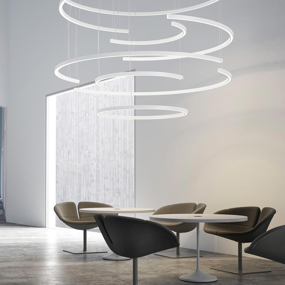 Brooklyn Round 360° white aluminium ring LED pendant lights at multiple heights above a seating area with round tables and dark lounge chairs.