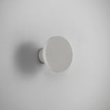 Arid A/01 round LED wall light in textured white aluminium, flat fluted disc on a short stem, mounted on a plain light grey background.