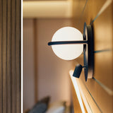 C-Ball W 2 Light Glass Sphere Wall Light in black finish, with a white glass sphere on a slim ring and a small reading spotlight, mounted on a wood-panelled wall.