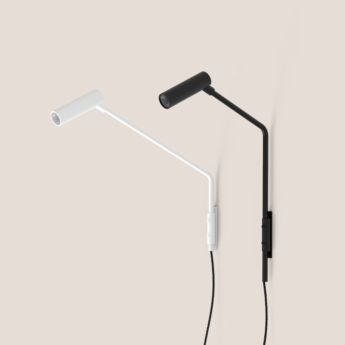 Nivia LED Wall Light with Reading Light in matt black, shown beside a white version, featuring an angled arm, cylindrical head and wall-mounted plate with cable, on a plain light background.