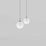 Mika Opal Glass Globe Pendant Light in Matt Black, two globe pendants of different sizes on black cables with matt black canopies, shown on a plain grey background.