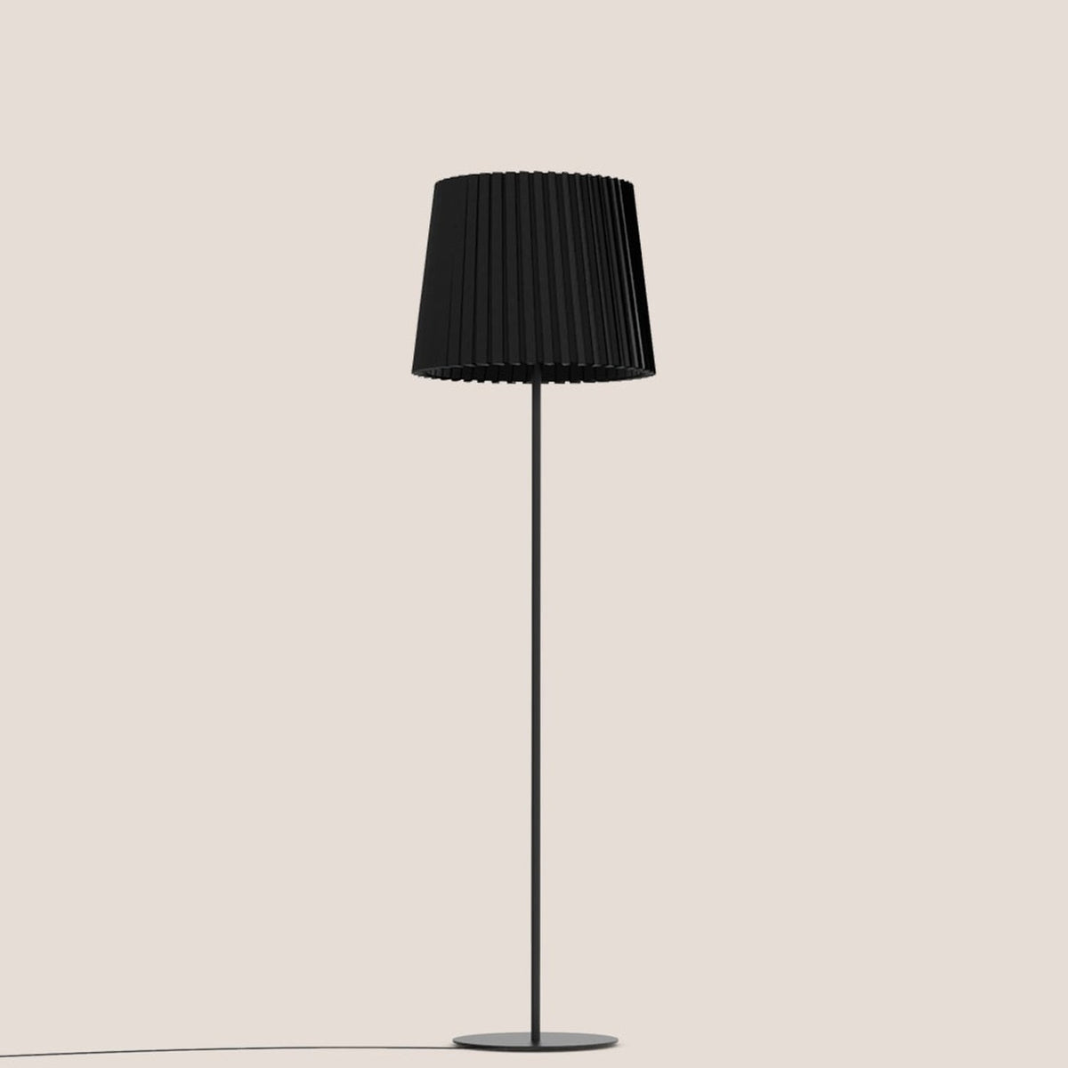 Kilma Ribbed Fabric Floor Lamp in matt black, featuring a pleated tapered fabric shade on a slim iron stem with round flat base, shown on a plain light background.