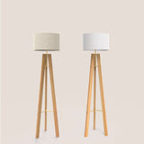Breeze Fabric Drum Tripod Floor Lamp in gold, shown in two linen shade shades beside a matching light grey version, both with wooden tripod legs on a plain background.