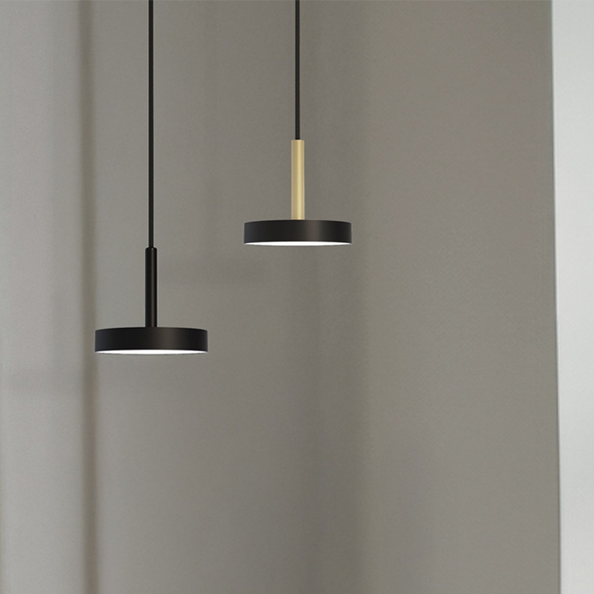 Rafaela Mono LED drum pendants with matt black shades and slim matt polished brass stems, shown at two heights against a plain grey background.