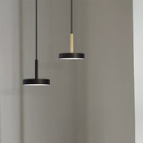 Rafaela Mono LED drum pendants with matt black shades and slim matt polished brass stems, shown at two heights against a plain grey background.