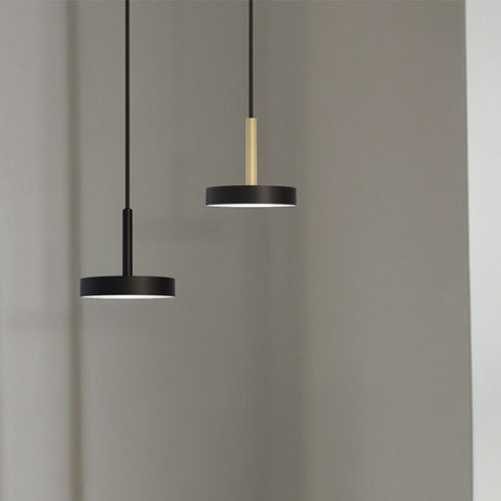 Rafaela Mono LED drum DALI pendant lights with matt black shades on slim black and polished brass stems, shown against a plain grey background.