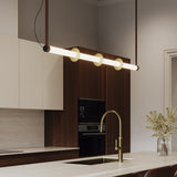 Roseline LED Ribbed Glass Linear Pendant Light in gold and brown, a long fluted glass bar with three gold discs, shown suspended above a kitchen island with warm white glow.