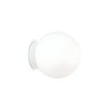 The Lyria Wall Light - White, 15cm showcases a sleek white spherical shape with a frosted glass finish, mounted on a straightforward circular base. It functions as a sphere diffuser, casting gentle, diffused illumination that complements its minimalist look against the plain white background.