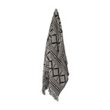 Gutte Geometric Throw in black, woven fabric with diamond and check patterns, fringed ends, hanging against a plain white background.