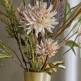 Artificial chrysanthemum stem in cream with one full spiky bloom and a smaller bud, serrated leaves, arranged in a vase among other faux stems.