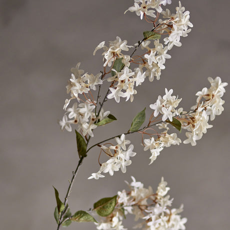 Artificial myrtle stem in white with clusters of small star-shaped flowers and rounded green leaves along slender branches, set against a plain grey background.