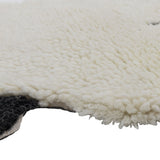 Close-up of the Dolly Sheep Wool Rug in cream, showing its deep curly wool pile and scalloped fleece-like edge against a plain white background.