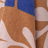Close-up of the Atle Leaf Cotton Throw in brown, showing woven cotton fabric with large rounded leaf shapes in blue and dusty pink.