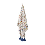 Cherry Floral Cotton Throw in multicoloured print with scattered flowers, textured cotton weave and navy tasselled corners, shown hanging against a plain white background.
