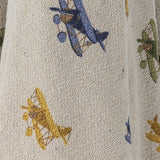 Close-up of the Plane Cotton Throw in beige, showing a woven cotton knit fabric printed with blue, green, and yellow biplane motifs.