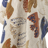 Anniversary Cotton Throw in Multi, woven cotton fabric with a textured weave featuring a printed multicoloured pattern of birds and wing shapes in blue, rust, and gold tones.