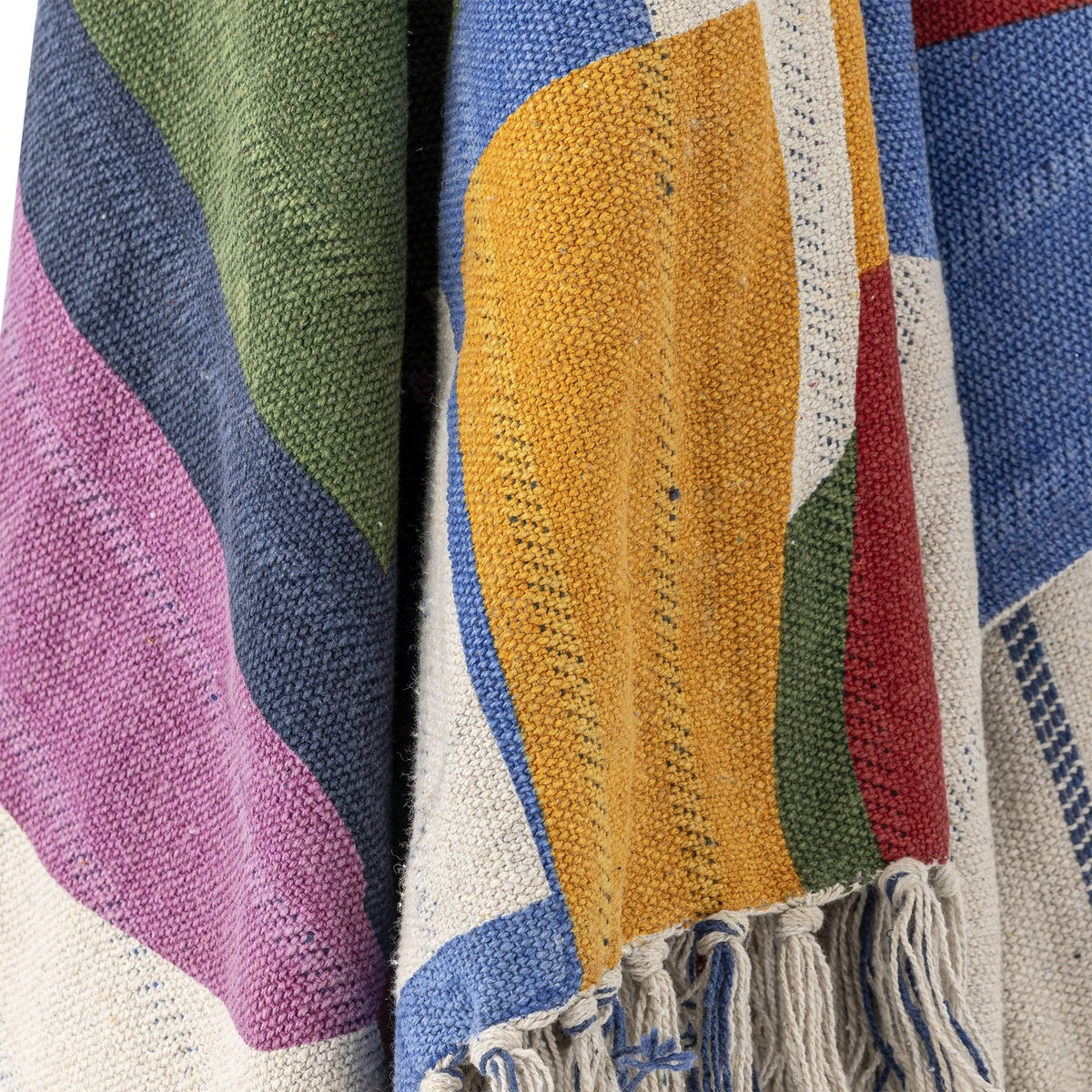 Close-up of the Artista Cotton Throw in multicoloured abstract shapes, showing a woven texture in mustard, blue, green, pink, and red with knotted fringe tassels.