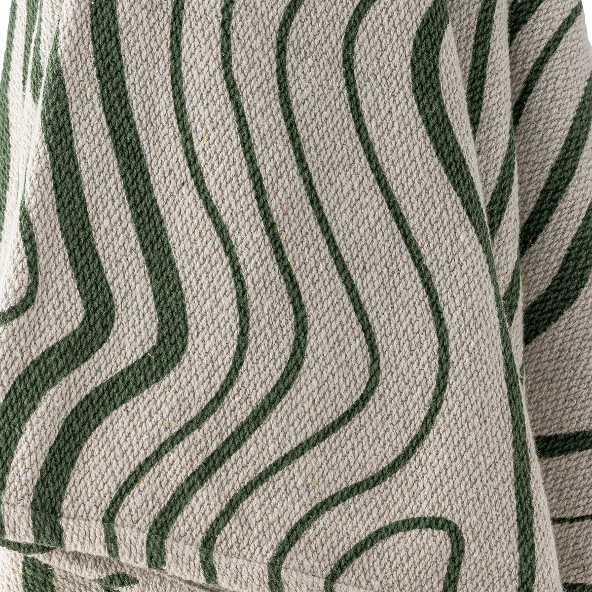 Close-up of the Woodsby Striped Cotton Throw in natural cotton with wavy green stripes resembling wood grain, showing the textured woven fabric and folded edge.