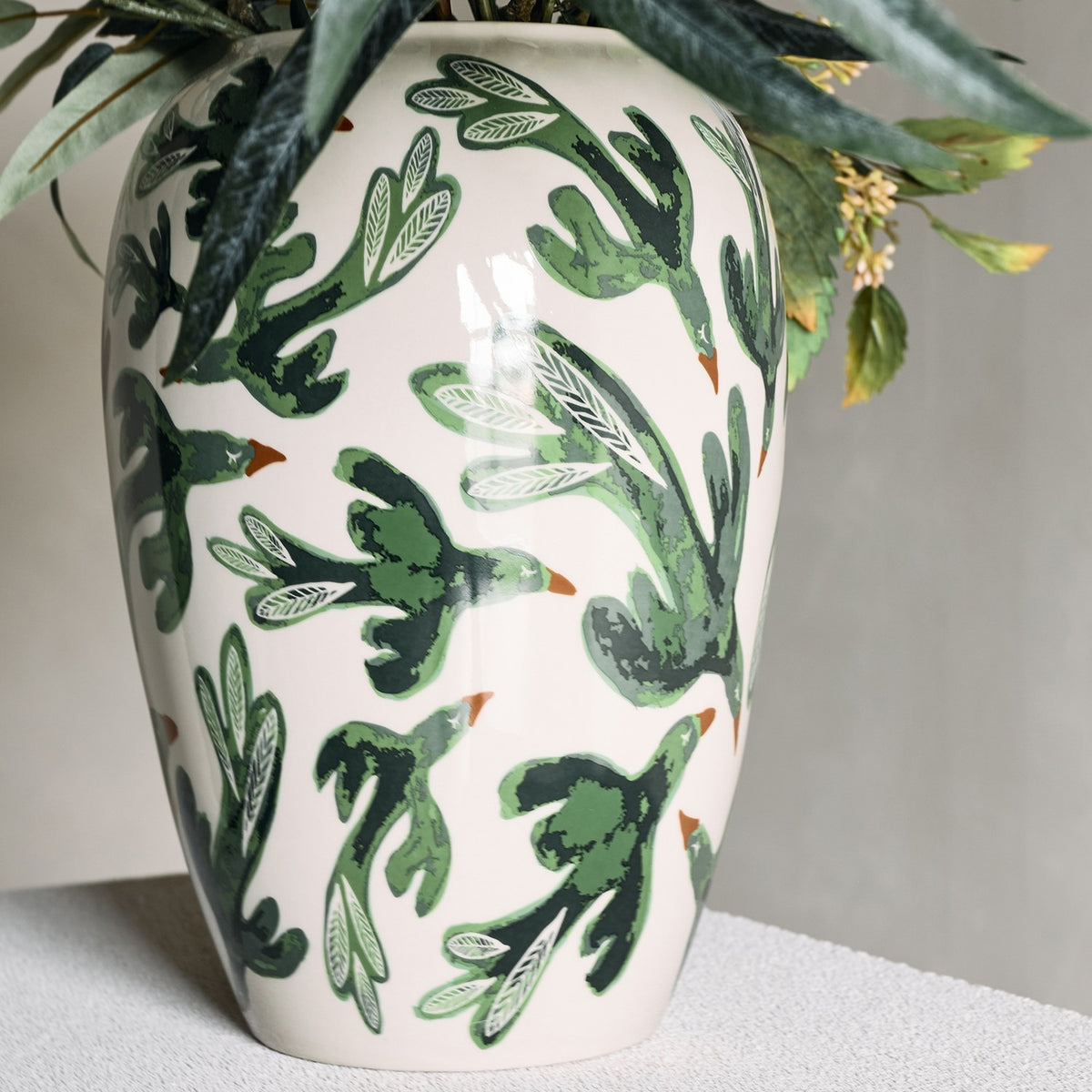 Birdliva Stoneware Vase 33cm in cream with green bird motifs and orange beaks, rounded shoulders tapering to the foot, shown with foliage against a neutral background.