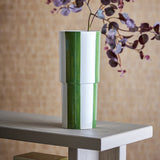 Floki Striped Stoneware Vase 31cm in green, with hand-painted vertical stripes on a glossy white ceramic body, shown on a wooden console table with a floral stem.