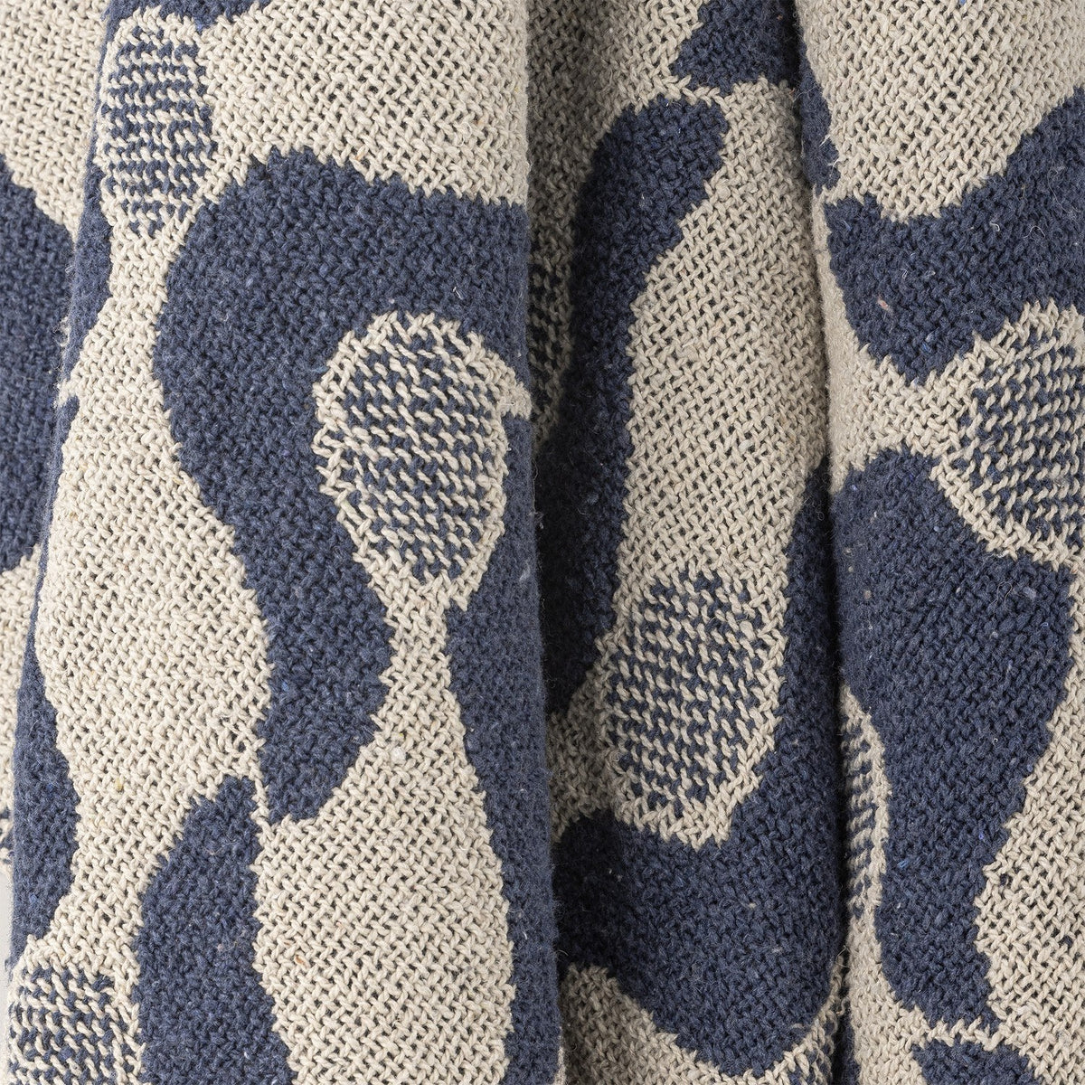 Close-up of the Santena Wavy Cotton Throw in blue, showing a woven cotton textured surface with a wavy pattern and small dotted circles.