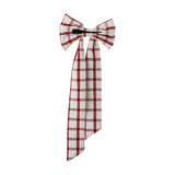 Ruby Cotton Christmas Bow in red check fabric with two rounded loops, a wrapped centre knot and long tails, fitted with a black clip, shown on a plain white background.