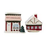 Gloria 2500ml ceramic Christmas storage jar shaped as a red "Hot Chocolate" shop, lid forming snow-topped roof with chimney, shown beside a matching red cottage-shaped jar on a white background.