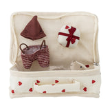Lara Cotton Rag Doll heart-print fabric suitcase open to reveal a knitted brown hat, striped shorts, a small round accessory, and the doll's fluffy ear peeking out.