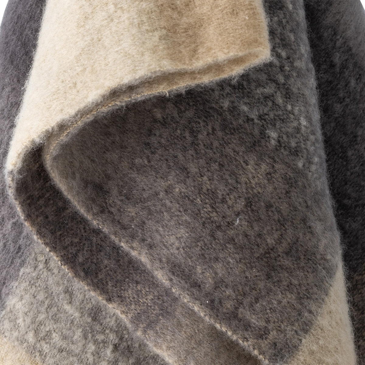 Close-up of the Hamisha Grey Throw, a fuzzy woven fabric throw in beige and grey block check with a visible folded edge and stitched border.