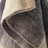 Close-up of the Hamisha Grey Throw, a fuzzy woven fabric throw in beige and grey block check with a visible folded edge and stitched border.