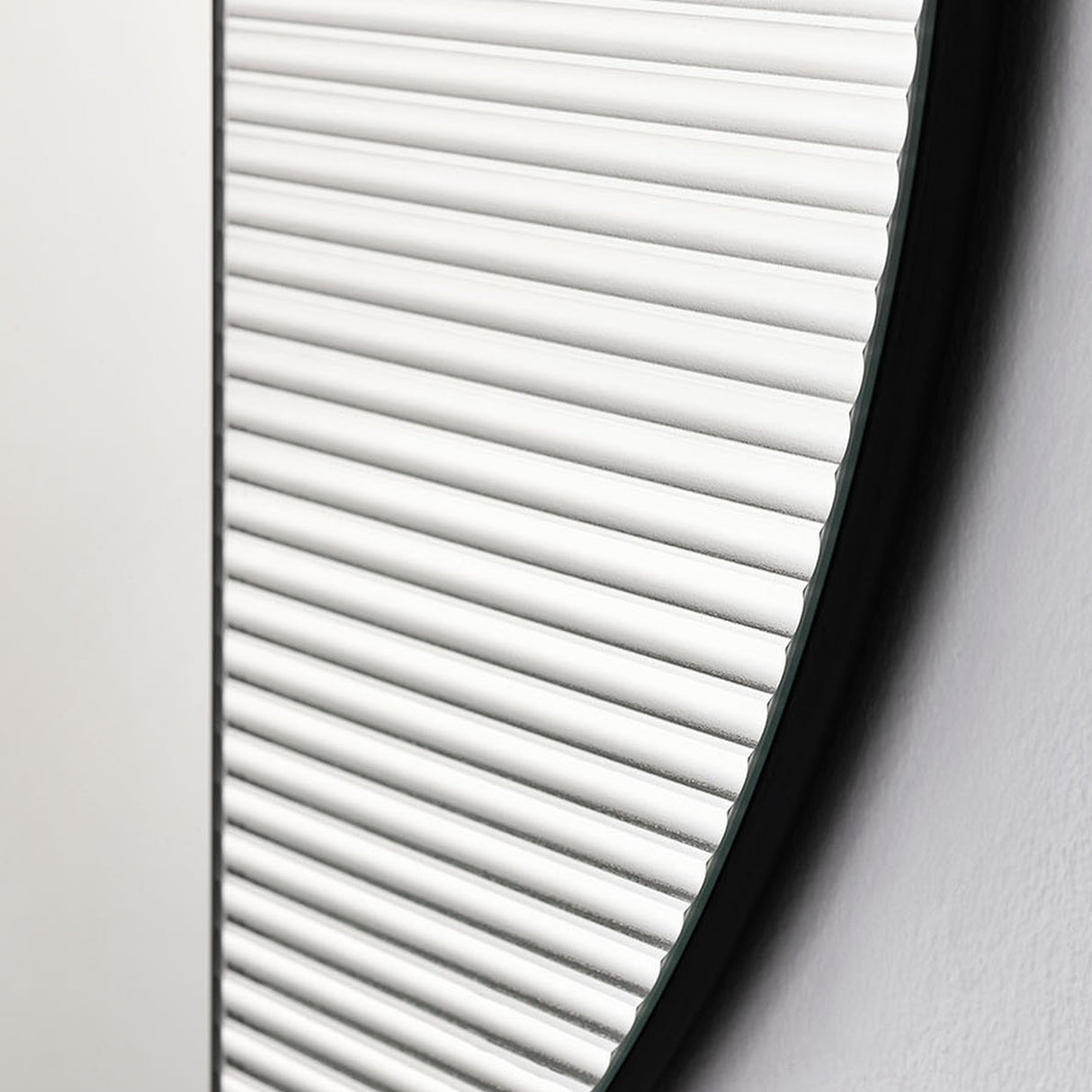 Close-up of the vertical ribbing running out to the rim, each groove catching the light along the edge of the glass.