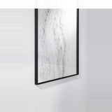 Close-up of the mirror seen at an angle on a ribbed wall, showing the slim black frame and the depth of the printed glass.