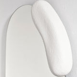 Close-up of the moulded white form at the left, its hand applied surface set against the curved edge of the glass.