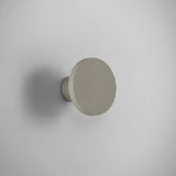 Arid A/01 round aluminium LED wall light in Textured Pebble Grey, fluted disc face on a short cylindrical stem, mounted on a plain light grey wall.