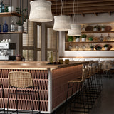 Syra 60 Aluminium LED Outdoor Pendant Lights in ivory white, three woven drum shades hung above a bar counter with rattan stools in a dining setting.