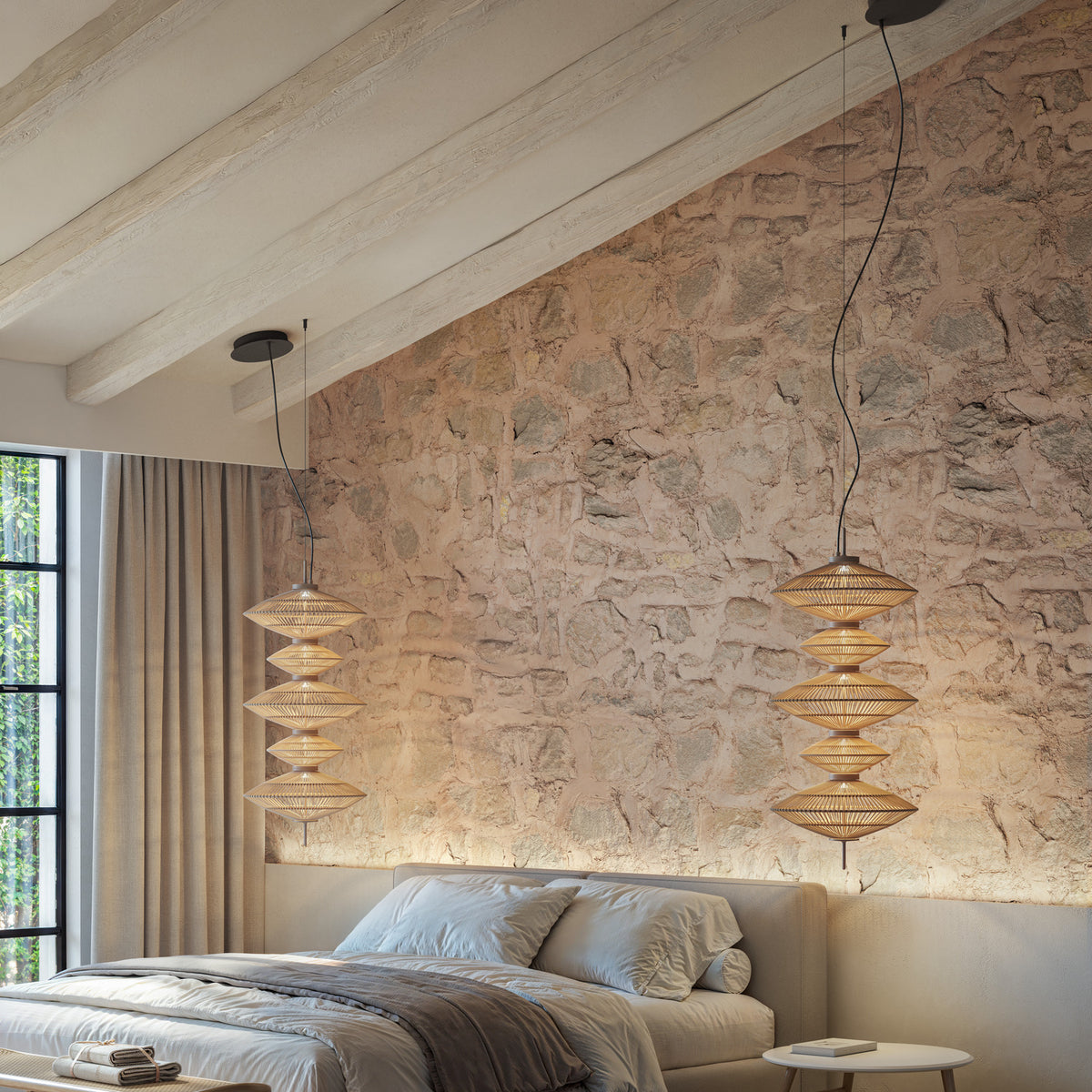 Yuyun S/5C LED pendant light with five stacked woven beige fabric tiers on a cable, shown in satin beige above a bedside table in a bedroom with a stone feature wall.