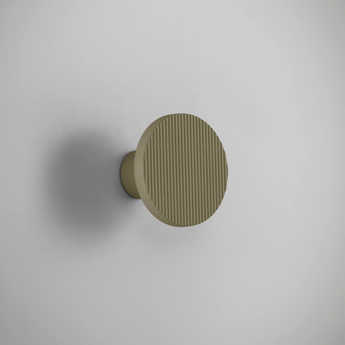 Arid A/01 round aluminium LED wall light with vertically fluted disc in Textured Olive Grey finish, mounted on a short stem against a plain light background.