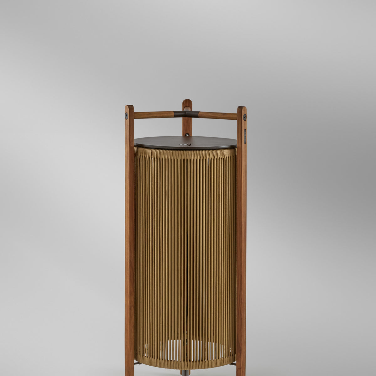 Kando P/111/R rechargeable outdoor floor lamp with sand nautical cord cylinder, teak wood frame, brown top disc, and three-legged base on a light grey background.