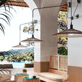 Nans 55 A/98 wall lights with long brown arms and woven cone shades in a beige fibre finish, mounted beneath an archway in a coastal-style outdoor seating area.