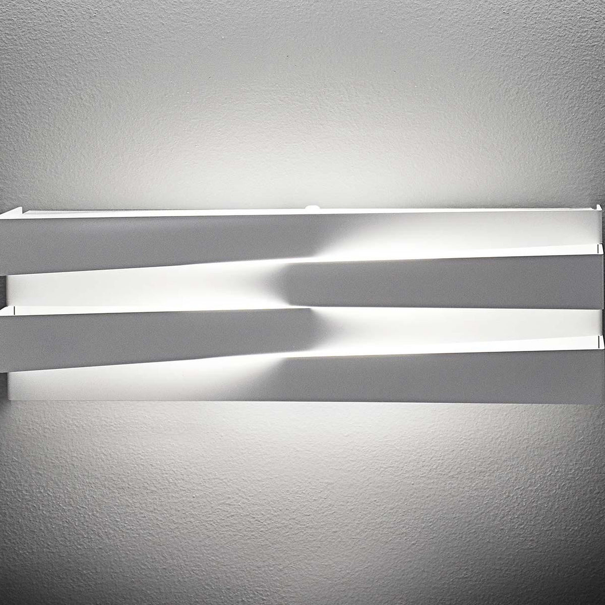 Cross Glass LED Wall Light 30cm in white finish, two crossing bars mounted on a wall, glowing warm light along the gap above and below, shown against a plain light grey background.