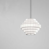 Mos 02 Ribbon Tiered Pendant Light with seven stacked pleated white translucent ribbon tiers on an iron frame, shown against a plain light grey background.