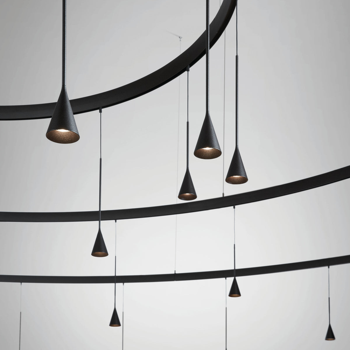 Skybell Circle Iron Ring LED Pendant Light in Ebony Black, showing curved iron rings with multiple cone-shaped heads suspended on slim cables against a plain light grey background.