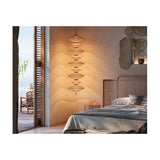 Yuyun S/7C fabric LED pendant light with seven stacked woven tiers in satin beige, hung beside a bed in a coastal-style bedroom near a window.